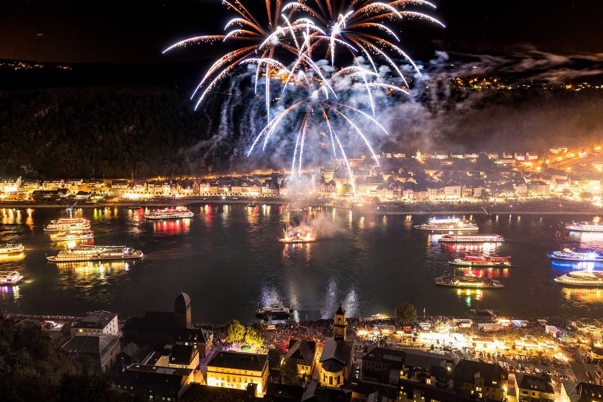 Viele beleuchtete Schiffe auf dem Rhein, Feuerwerk im Hintergrund