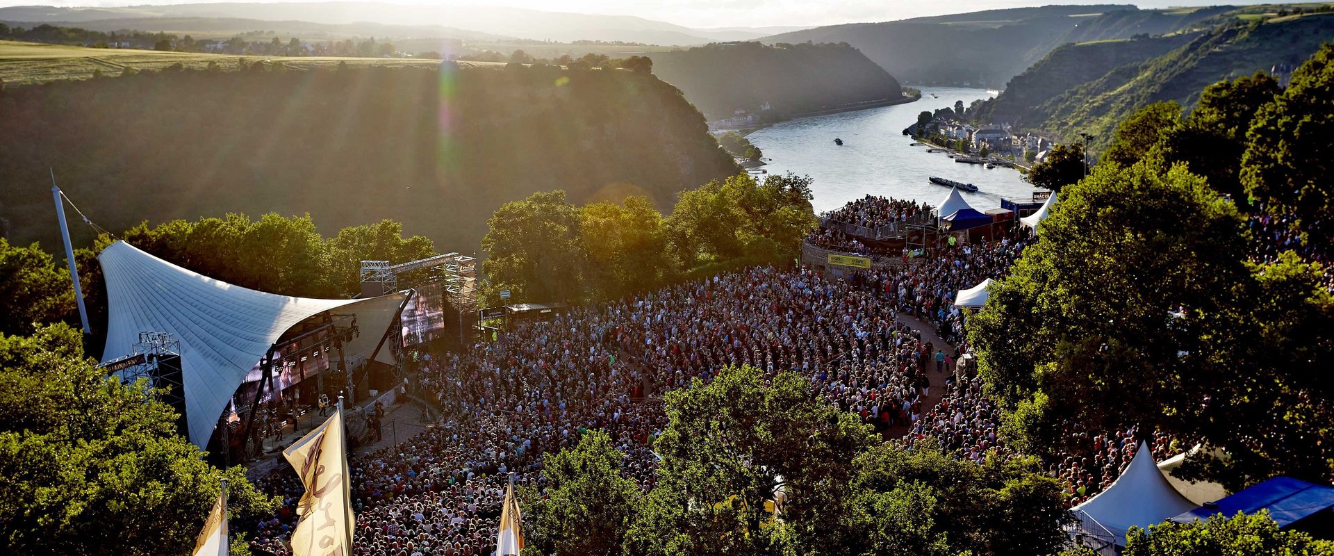 Freilichtbühne mit Publikum vor der Kulisse des Rheins